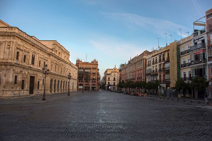 The carved town hall and tall old houses around an empty, cobbled square in early morning light.